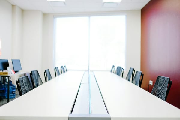 Minimal white conference table with black office chairs, the room where Kickoff alignment happens