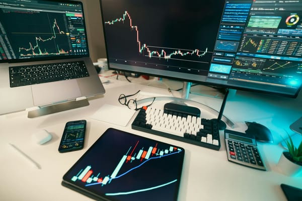 Multiple monitors displaying real-time financial charts at a sophisticated trading desk